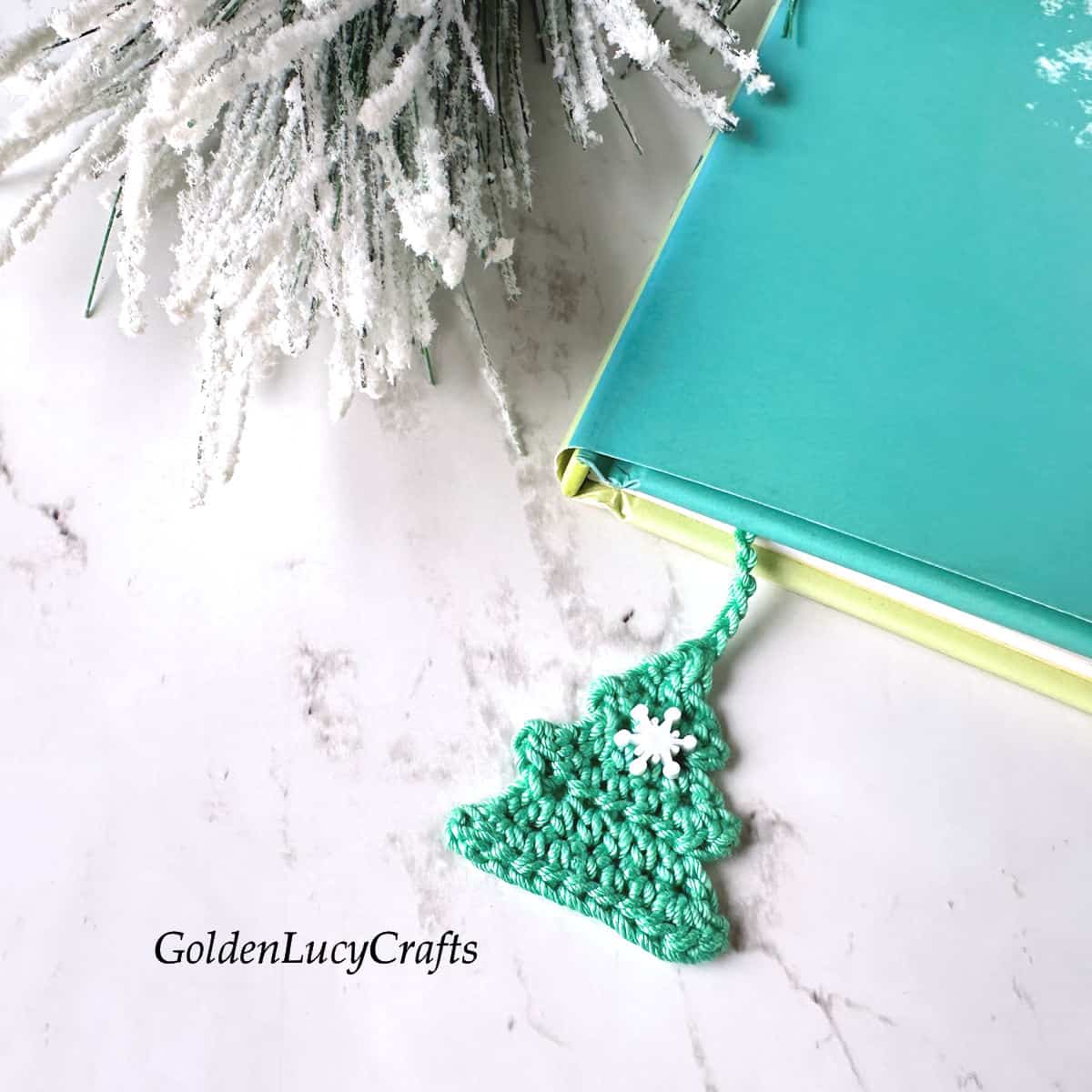 Crochet bookmark in the shape of a Christmas tree placed in the book.