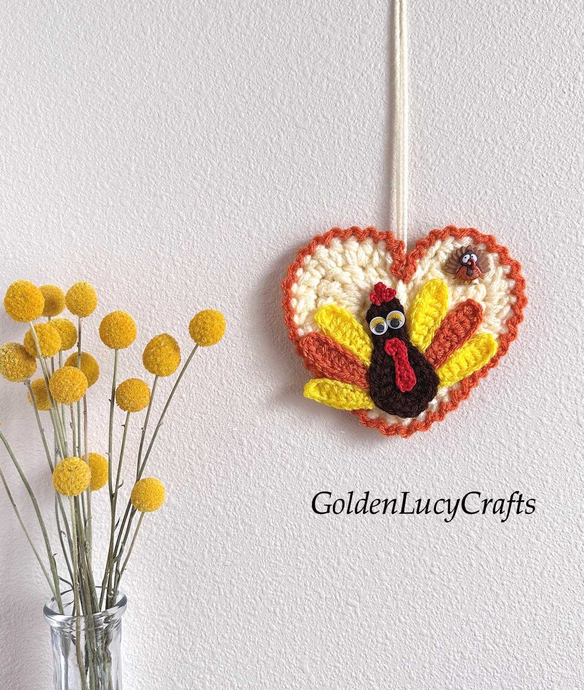 Crochet turkey ornament hanging on the wall.