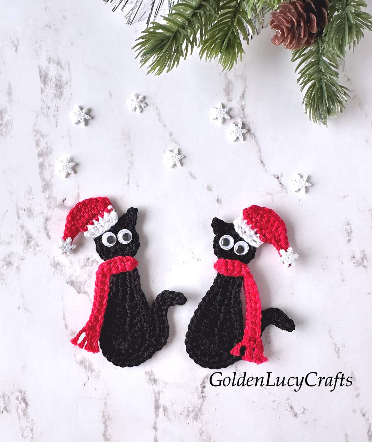 Crochet appliques - two black cats with googly eyes dressed in Santa hats and red scarves.