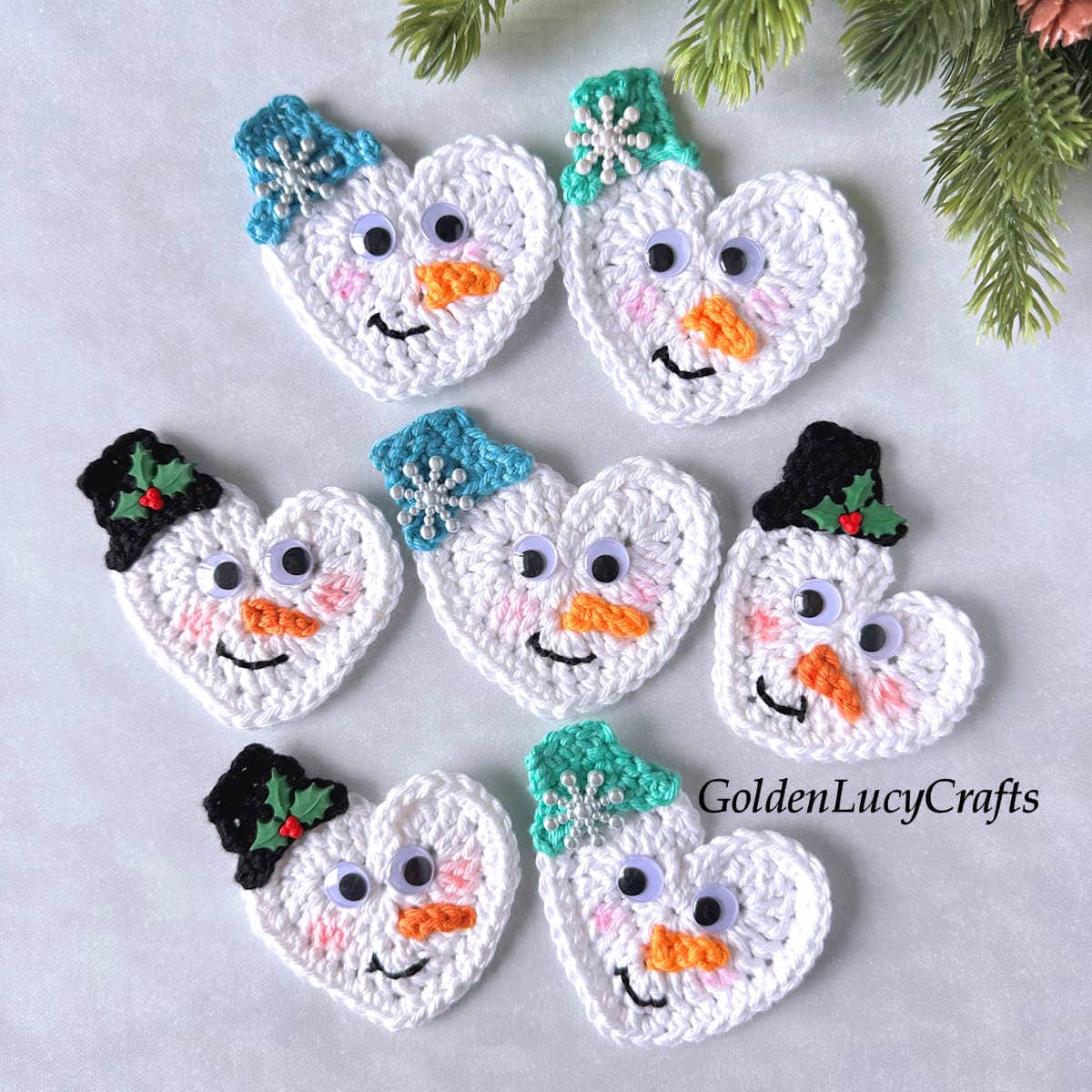 Seven crocheted heart-shaped snowman faces.