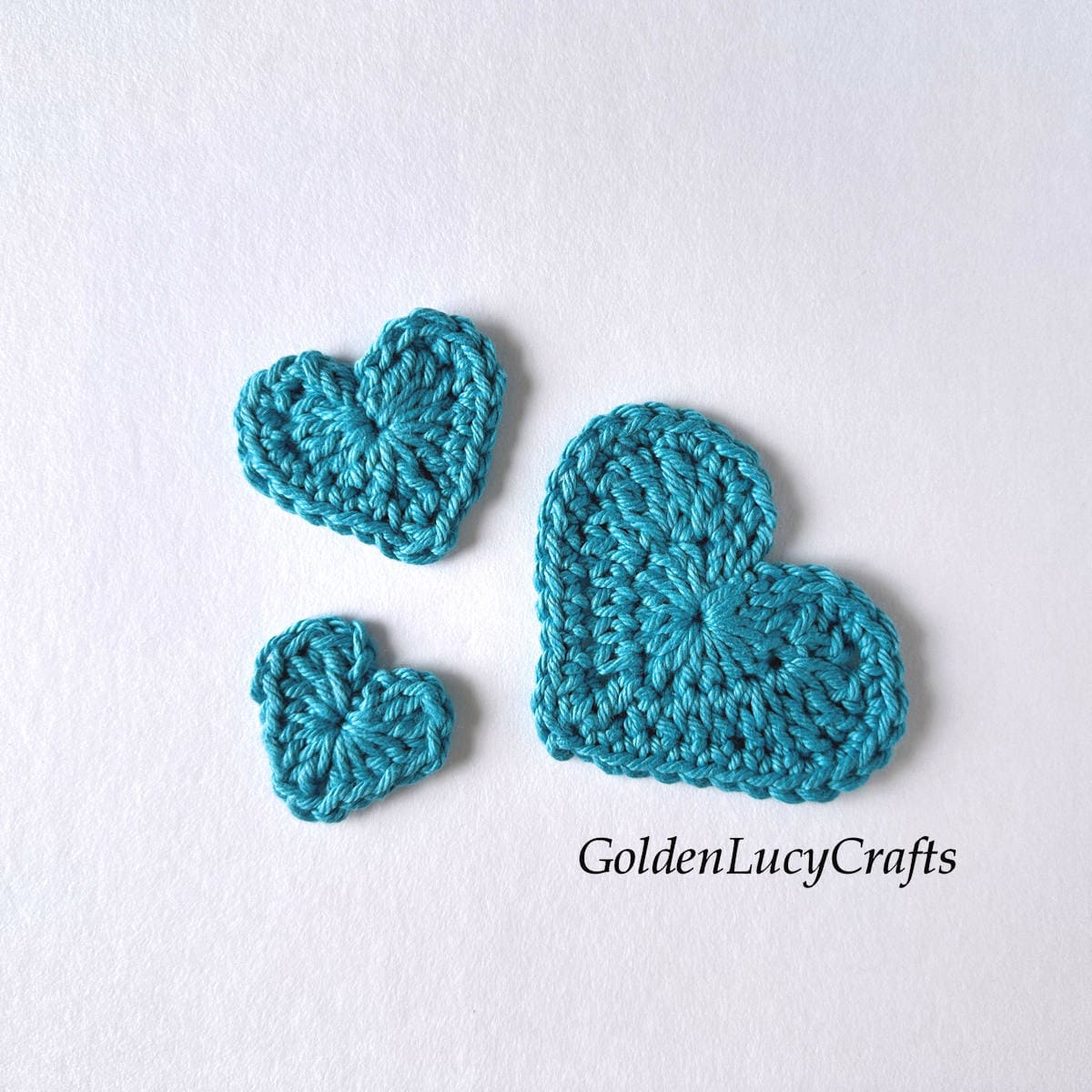 Three crocheted hearts in varying sizes, all in an aqua color.