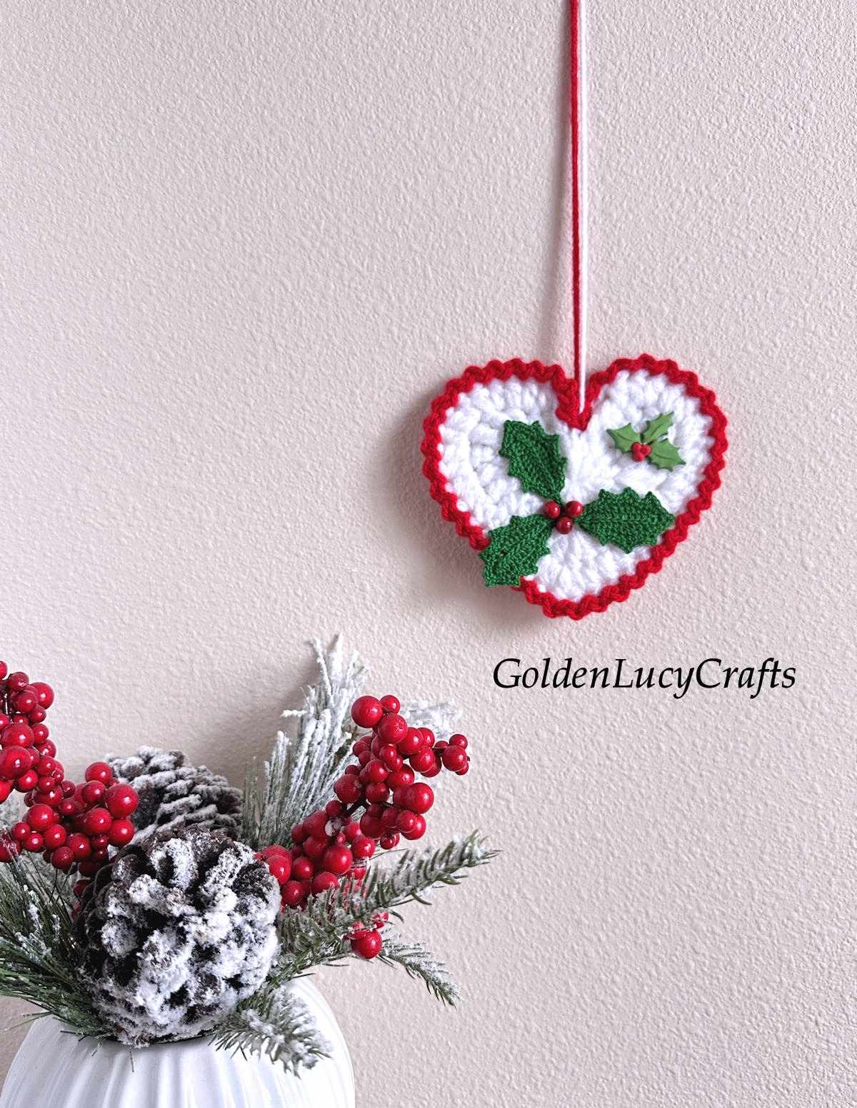 Crochet holly ornament hanging on the wall.