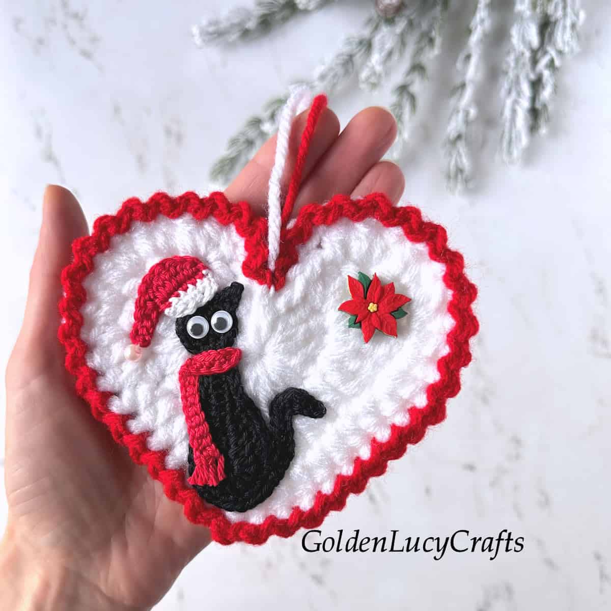 Crochet Santa cat ornament in the palm of a hand.