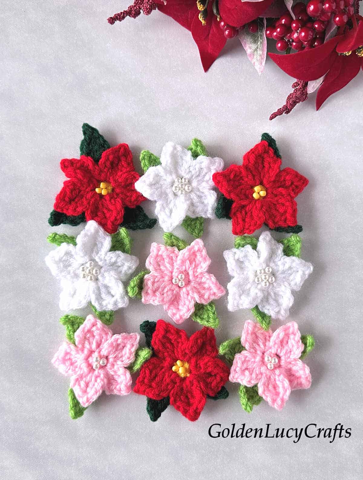 Nine crochet poinbsettia flowers in red, white and pink colors.