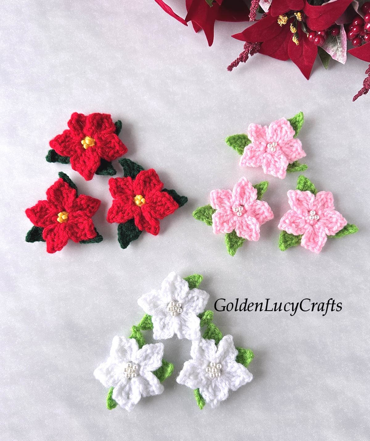 Nine crocheted poinsettia flowers in red, white, and pink colors.