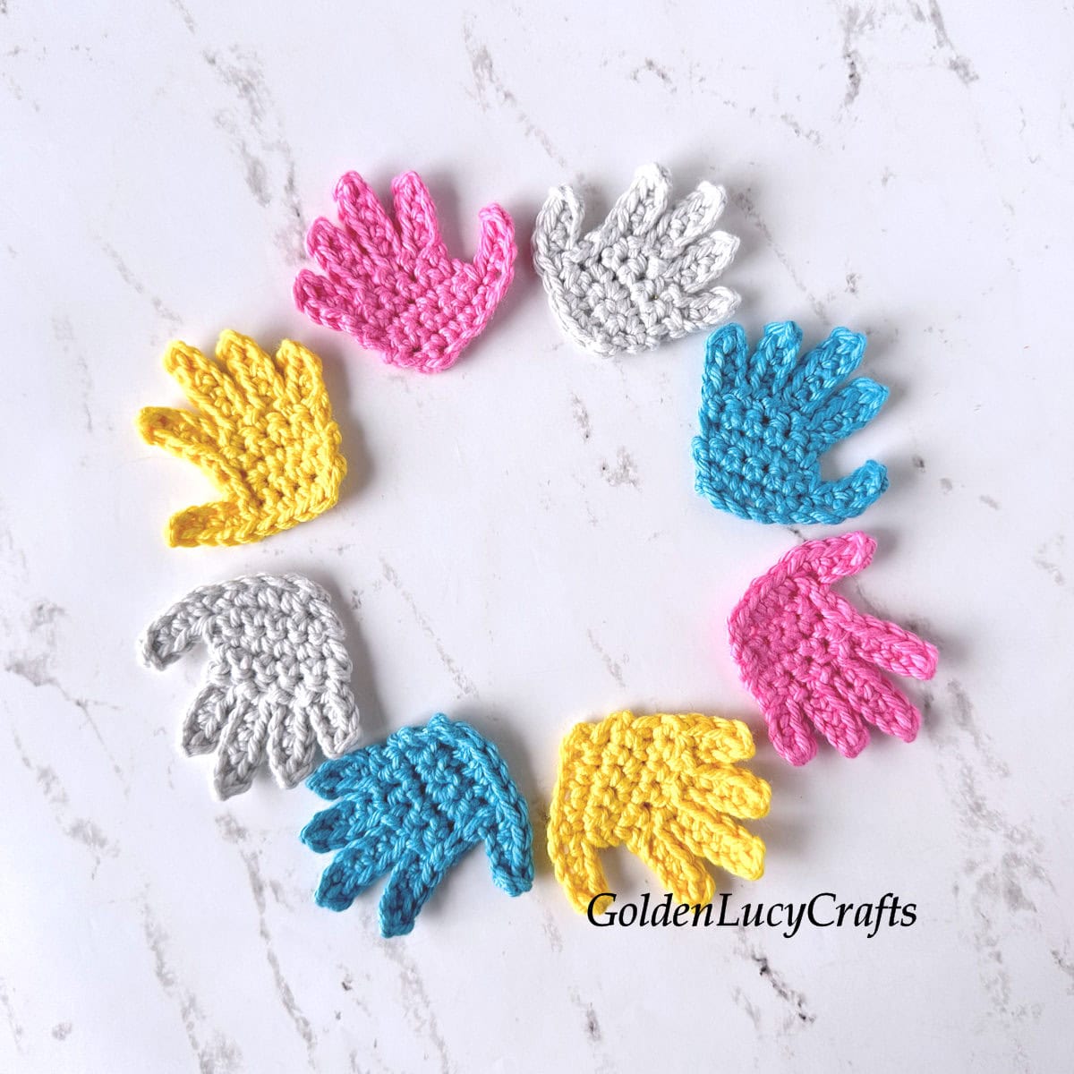 Crochet hand appliques in yellow, pink, blue, and gray, arranged in a circle.