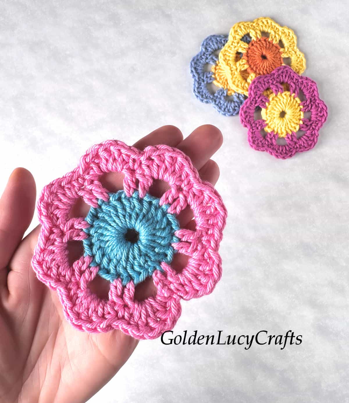 Crocheted flower motif in the palm of a hand.