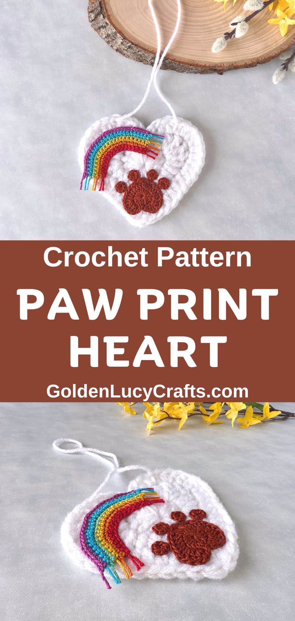 A white crocheted heart ornament featuring a paw print and a rainbow, a close-up picture.
