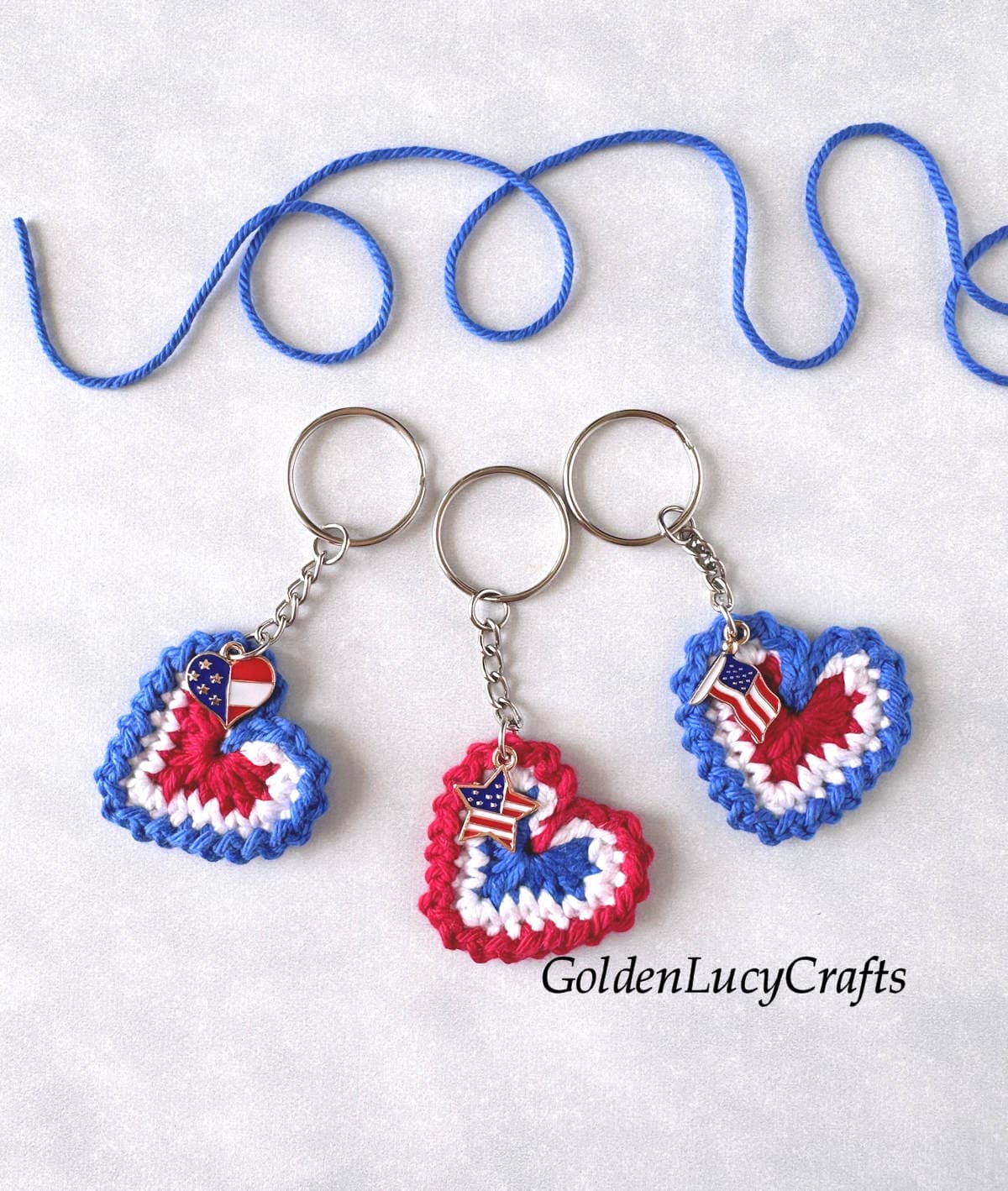 Three crocheted patriotic keychains made with red, white and blue yarns and embellished with small patriotic charms.