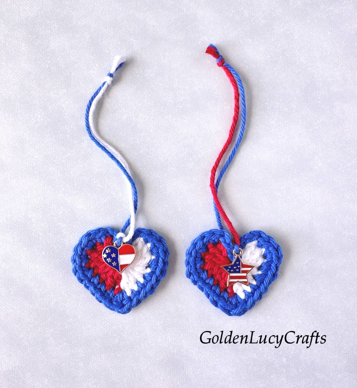 Two crocheted patriotic heart ornaments with charms.