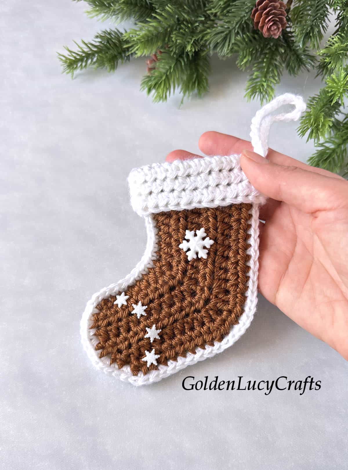 Crocheted gingerbread stocking held by hand.