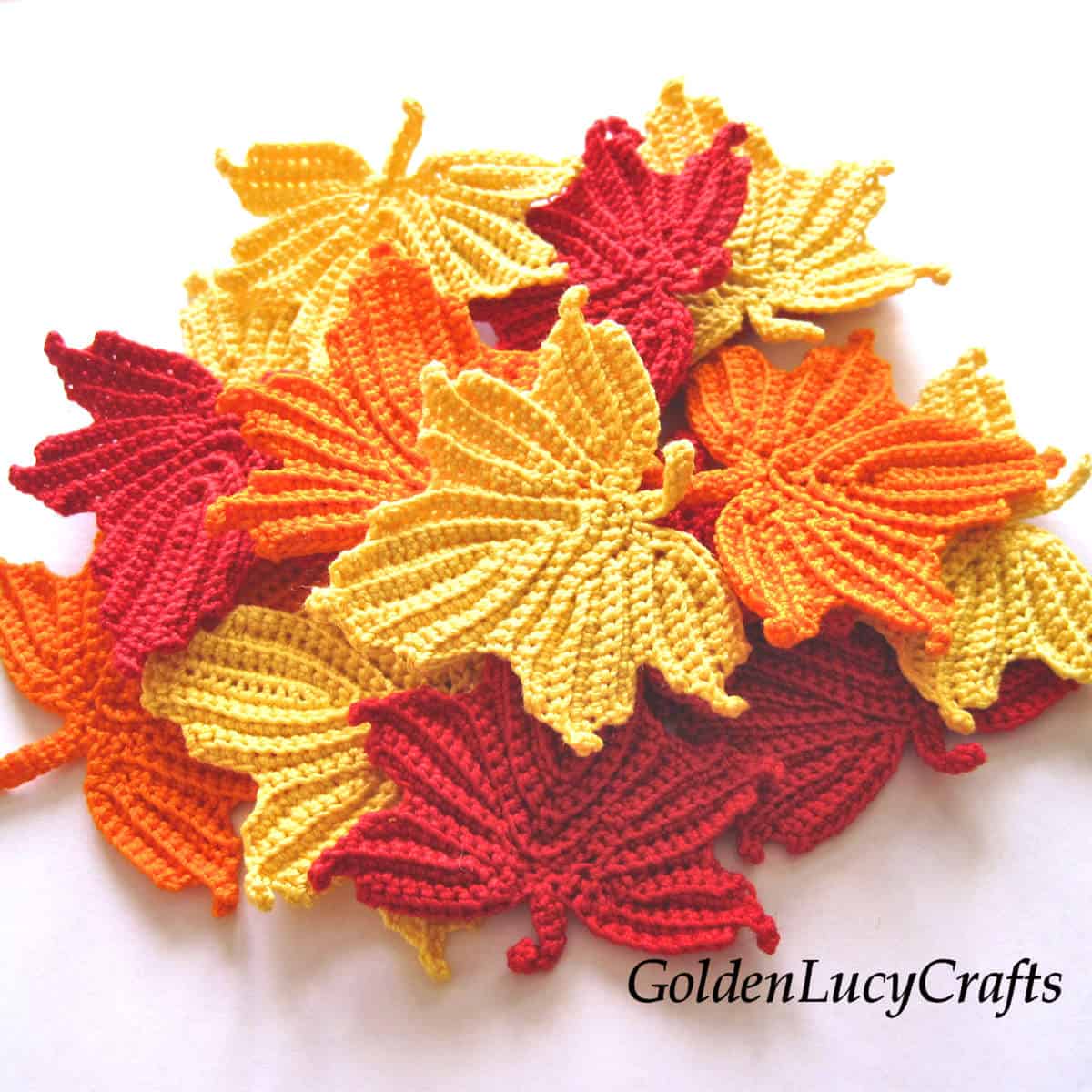 A pile of crocheted maple leaves in red, yellow, and orange.