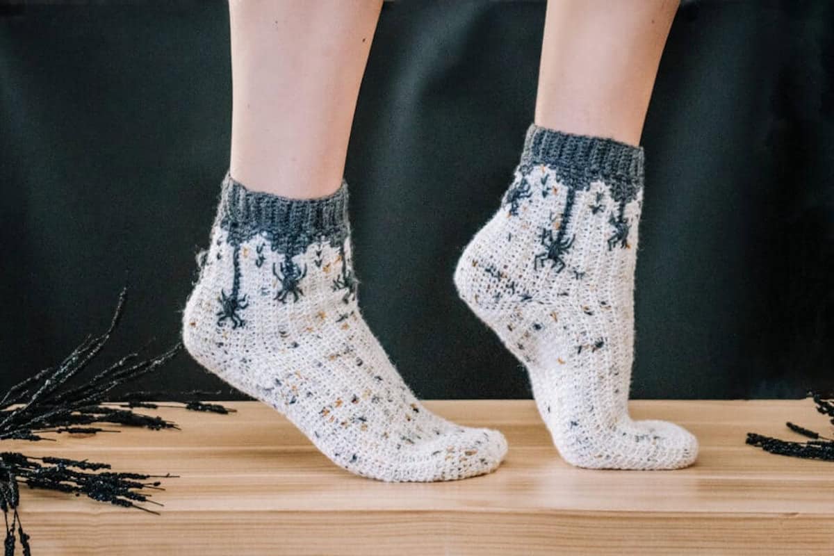 Two feet dressed in crocheted spider socks.