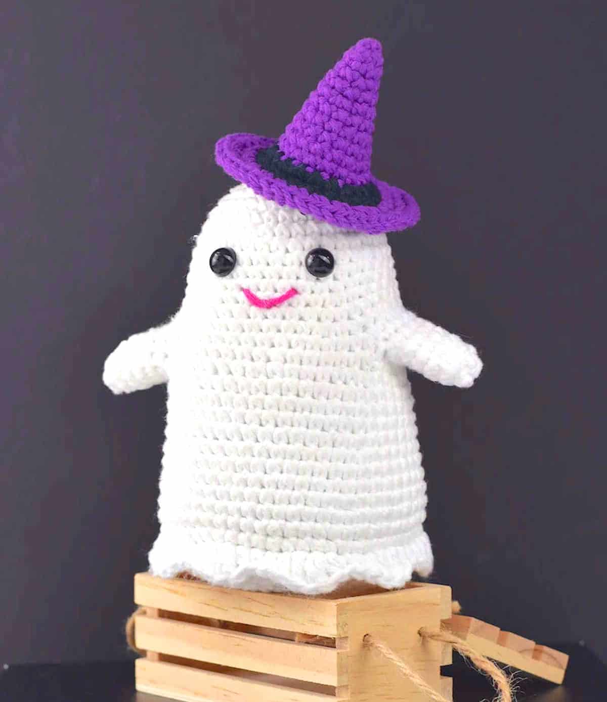 Crocheted ghost in a purple hat.
