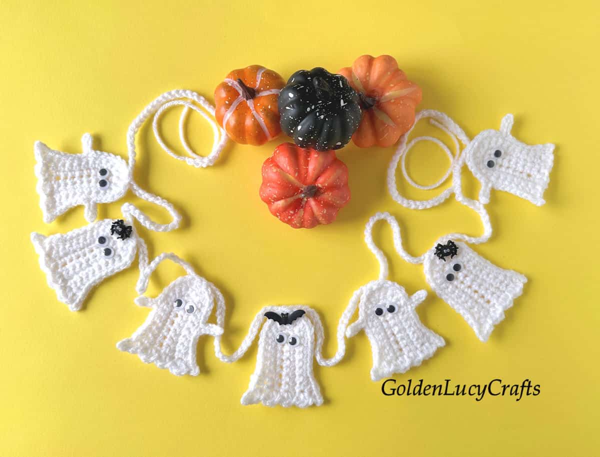 Crocheted ghost garland on yellow background.