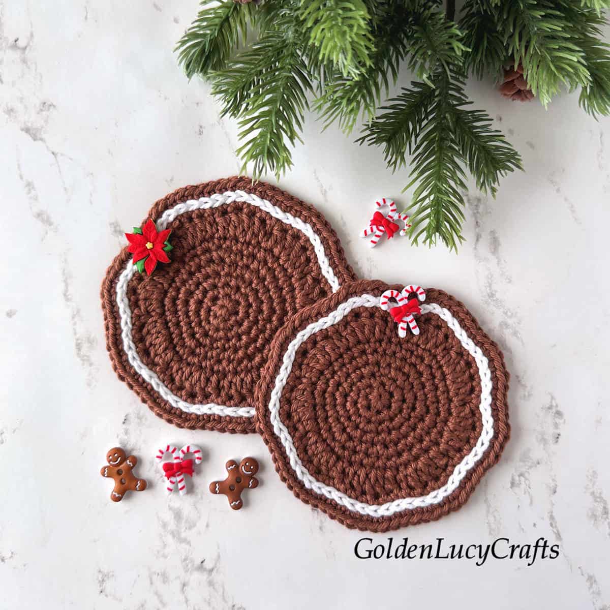 Two crocheted gingerbread-themed coasters in brown and white, embellished with Christmas decorative buttons.